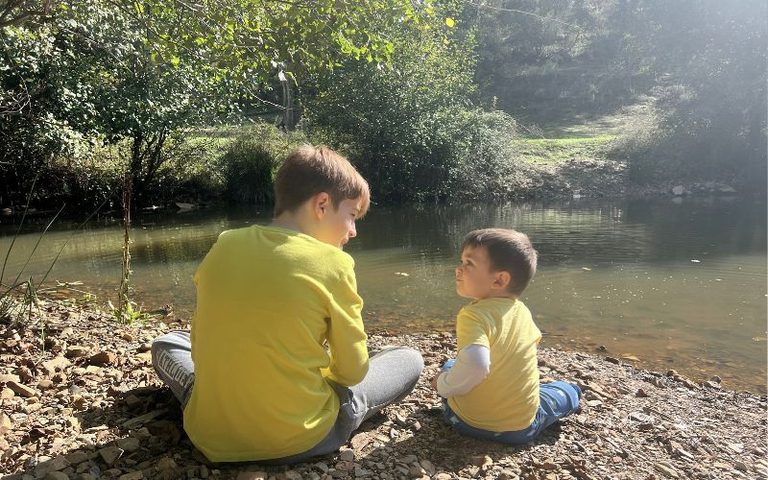 Dos niños jugando junto al río durante una salida de otoño