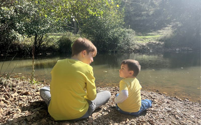 Dos niños jugando junto al río durante una salida de otoño